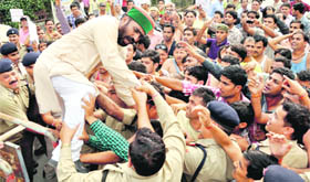 Mantri Prasad Naithani, former Congress minister, tries to jump across the barricades during a protest by MGNREGA workers at the Secretariat in Dehradun on Thursday. 