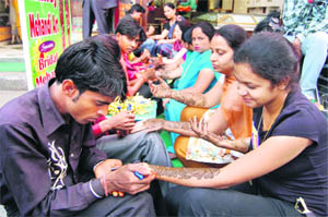 Women get mehndi applied on their hands ahead of Karva Chauth in Dehradun on Thursday. 