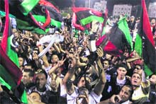 Gaddafi opponents wave Libyan flags at the Martyrs Square in Tripoli late on Wednesday as they celebrate the arrest of his son Motassim. 