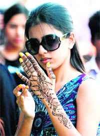 A girl admires the intricate mehndi on her hand on the eve of Karva Chauth in Mohali on Friday.
