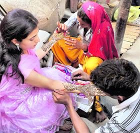 A woman gets her hands decorated with henna ahead of Karva Chauth in Jammu on Friday.