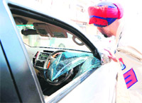 A cop examines the car from which a laptop was stolen in Ludhiana on Friday