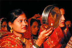 A woman looks at the moon through the sieve before ending her fast on Karva Chauth.