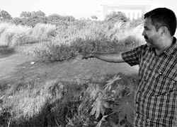 A resident points to a pond of stagnant and dirty water