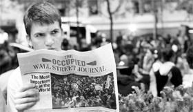 An "Occupy Wall Street" campaign demonstrator reads "The Occupied Wall Street Journal", a newspaper published by the campaign.