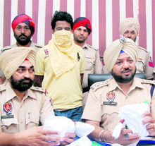 The accused, Jeevan (face covered), flanked by policemen in Jalandhar on Saturday