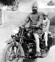 Jagjit Singh straddled across a Bullet motorcycle behind his father
