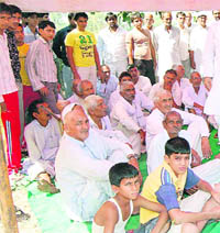 Residents sit on a dharna against construction of the Aasudha-Kharkhoda road at Aashodha village in Jhajjar on Sunday