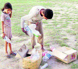 Children gather empty bottles from a school ground at Ahmedgarh.