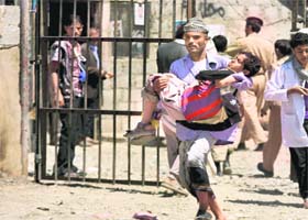 A man carries a young boy during the clashes between protesters and security forces in Sanaa on Sunday