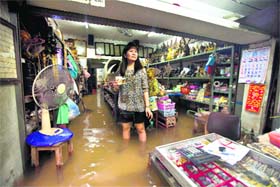 A Thai shopkeeper stands in floodwaters at an inundated market in Bangkok