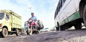 Traffic passes through the damaged national highway in Gurgaon.