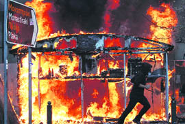 A demonstrator runs past a burning newspaper kiosk in Athens on Wednesday