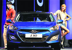 Korean models pose with Hyundai Motor's new hatchback i30 at its launch in Seoul on Thursday. Hyundai will begin selling a revamped version of the compact car this week to help it better compete against cars such as the Volkswagen Golf, the firm said