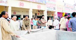 Fire brigade employees fill open water tanks in front of shops at Patakha Market in Amritsar on Saturday