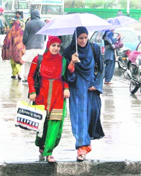 Girls with an umbrella walk during rain in Srinagar on Saturday
