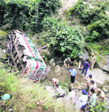 Police and rescue officials gather near the wreckage of the bus that fell into a gorge in Nandini, some 20km from Jammu, on Sunday.