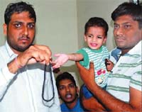 The kidnapped boy Kartik with his family members after his release on Monday. His father shows a black necklace that was found hanging around the boys neck.