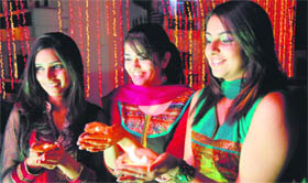 Three girls with earthen lamps on the eve of Diwali in Dehradun on Tuesday.