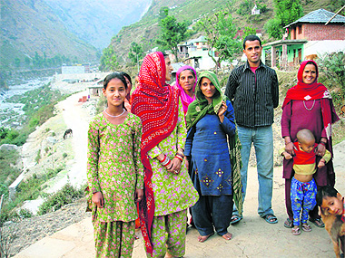 Poor villagers stand outside their damaged houses in the village in Palampur.