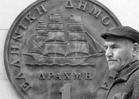   A man passes in front of a huge replica of a one drachma coin in Athens, Greece. 