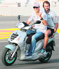 Mercedes driver Michael Schumacher (L) rides a scooter as he inspects the F1 track on Thursday. 