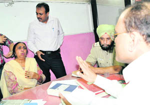 Usha Sood, along with her son Rajiv Sood, explains her point to a bank official in Sector 37, Chandigarh, on Friday. 