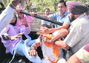 Policemen try to stop unemployed linemen from raising anti-government slogans during the CMs speech.