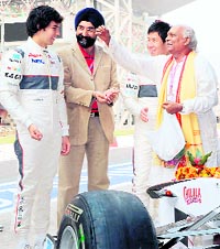 Sauber drivers Kamui Kobayashi (2nd R) and Sergio Perez (L) and a representative from the team's sponsor, Amul, receive blessings from a priest on Friday