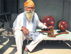 Sant Singh with parts of charkhas manufactured by him, which are of no use today 