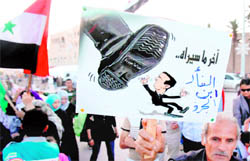 A man holds an anti-Syrian President Bashar al-Assad poster that reads in Arabic "The last thing that the mouse, son of the rat, will see" during a protest