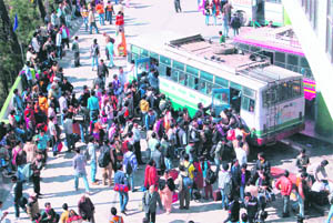 Passengers rush to a bus at the New ISBT in Shimla on Sunday as the number of buses is limited.