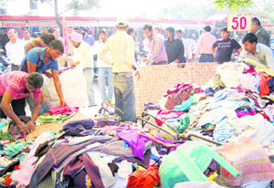 The staff of the enforcement team of the municipal corporation lift readymade garments during an anti-encroachment drrive at the Sadar Bazar in Sector 19 of Chandigarh on Monday.