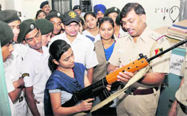 Students see a gun at the Sector-26 police station as a part of the Global Police Week in Chandigarh on Monday. 