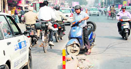 A scooterist tries to cross through the broken divider on Lawrence Road in Amritsar. 