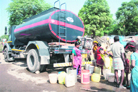 People wait in a queue to fill their buckets from a water tank in the Channi Rama area of Jammu. 