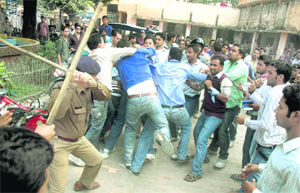 A policeman cane charges warring groups of students at DAV PG College in Dehradun on Thursday. 