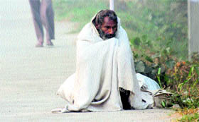 An old man sits along the NH 1 on a cold and foggy morning in Karnal.