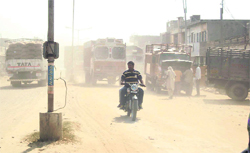Vehicles ply amid a cloud of dust at the Raikot road in Jagraon.