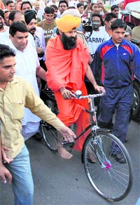 Yoga Guru Swami Ramdev rides a bicycle through a busy street in Jalandhar on Saturday