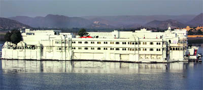 The Lake Palace, constructed in white, glimmers in the sunshine, and is reflected in the waters of Lake