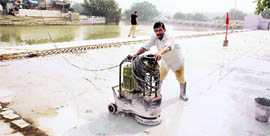 Workers engaged in laying marble slabs at the holy pond of Ramteerath temple.
