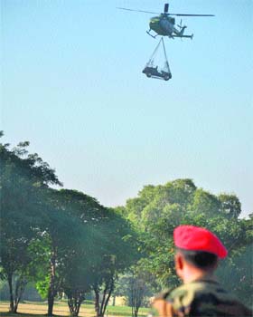 A soldier watches a Dhruv helicopter airlifting a jeep during an air show in Akhnoor as part of the silver jubilee celebrations of the Army Aviation Corps