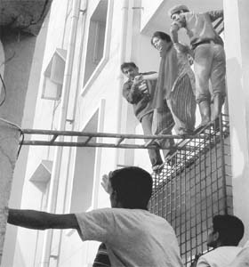 Fire personnel rescue a woman stuck in an apartment after a major fire broke out at a shopping complex at Kondapure in Hyderabad on Sunday