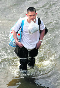 A man holding his belongings wades through a flooded street in Bangkok on Sunday.