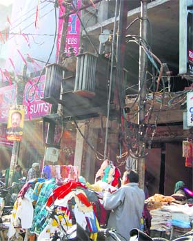 A vendor puts up a cloth stall under an electricity transformer with loosely hanging wires in the Katra Jaimal Singh area, Amritsar