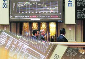 People walk past screens at a bourse in Madrid on Monday. European stock futures pointed to a weaker open for equities on Monday as political uncertainties in highly-indebted Italy and Greece raised fresh concerns that the region's debt crisis would intensify and threaten a fragile global economic recovery.
