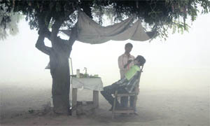 A roadside hair dresser at work on a foggy morning in Karnal. 