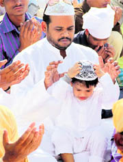 A child with his father offers Eid prayers at a mosque in Jalandhar on Monday.