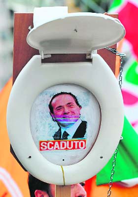 A demonstrator holds a toilet seat with a photo of Italian Prime Minister Silvio Berlusconi that reads finished at a protest in Rome
